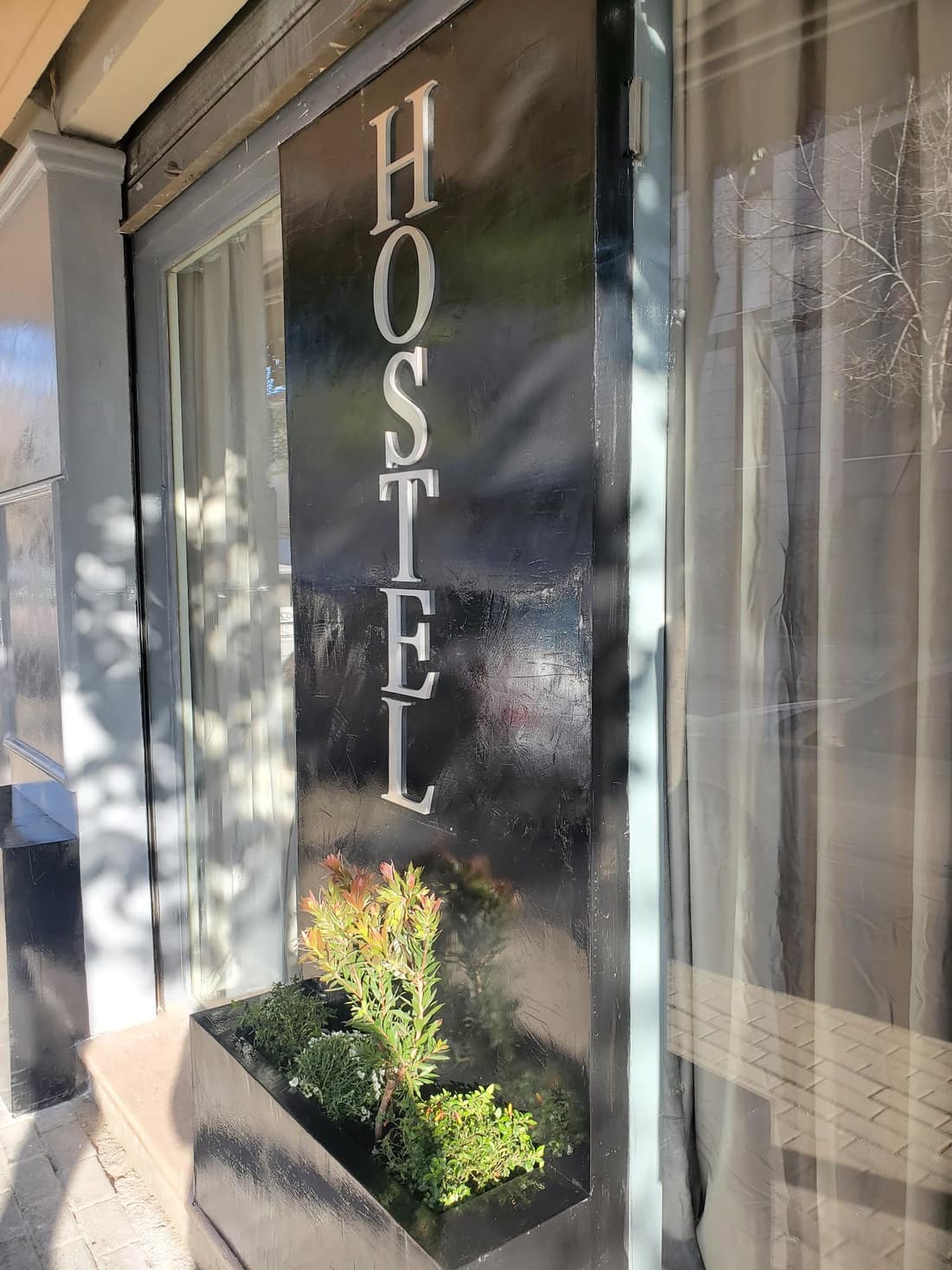 Shop window with HOSTEL lettered vertically and a planter below