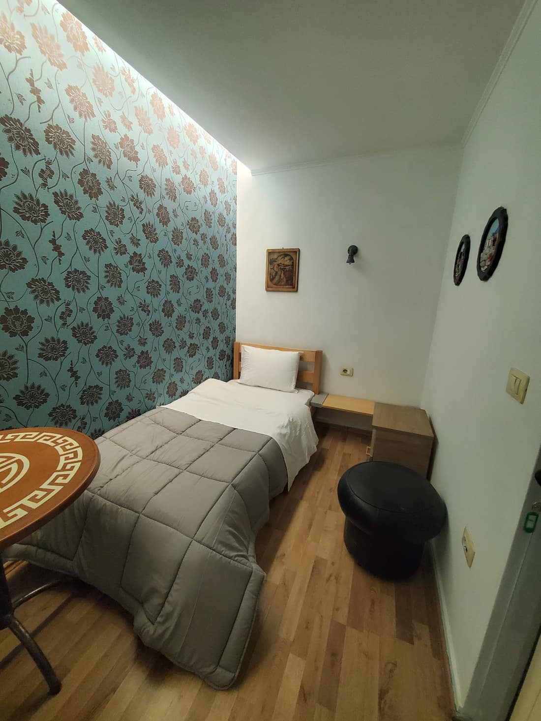 Single room with patterned blue feature wall and wooden floor